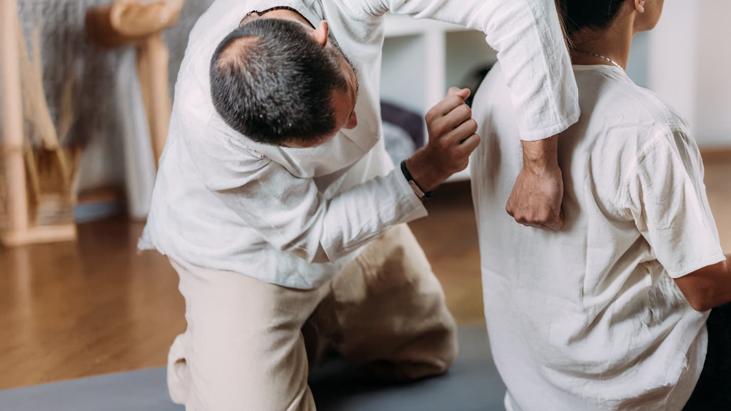 Professional Back Massage Therapy Session Male massage therapist applying pressure to female client's upper back during therapeutic bodywork session