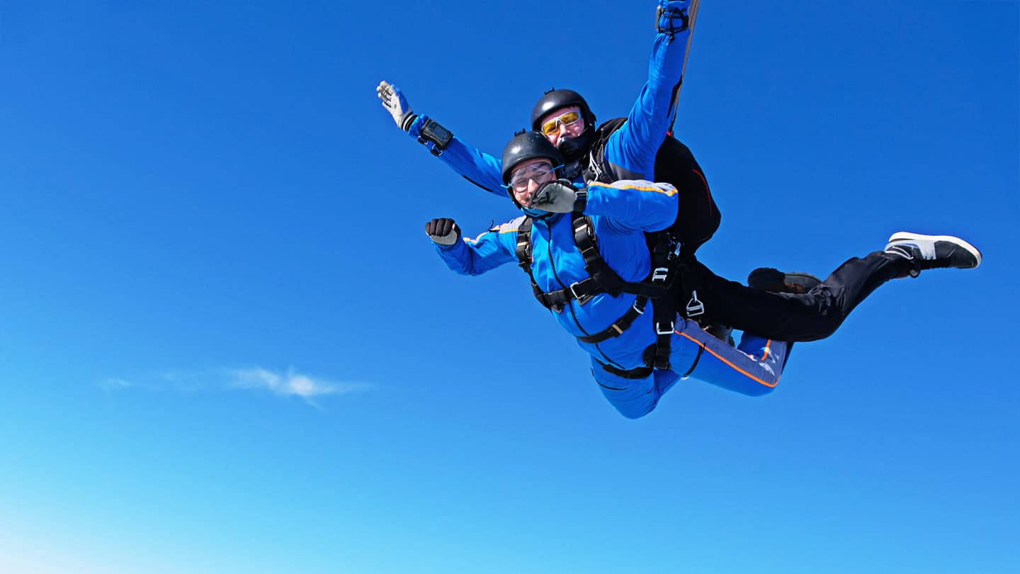 Tandem Skydiving Freefall Adventure Two people in tandem skydiving freefall against clear blue sky
