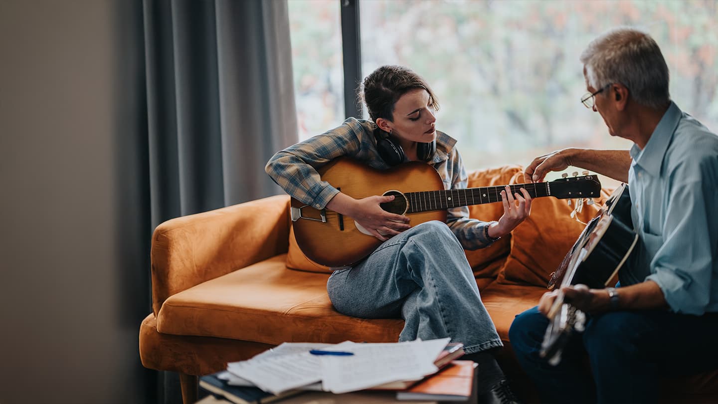 Acoustic Guitar Lesson with Instructor Young woman playing acoustic guitar during a lesson with an older instructor