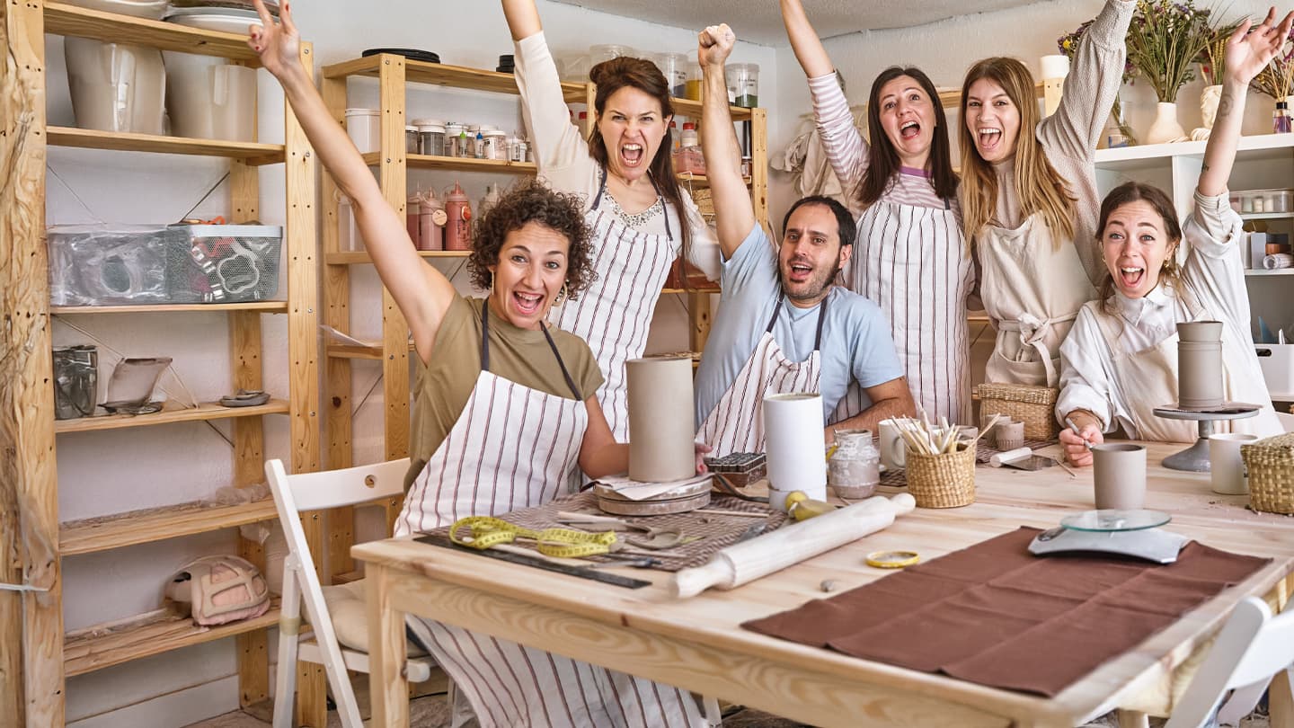 Joyful Pottery Class Celebration Group of enthusiastic pottery students raising arms in celebration at a ceramic workshop studio