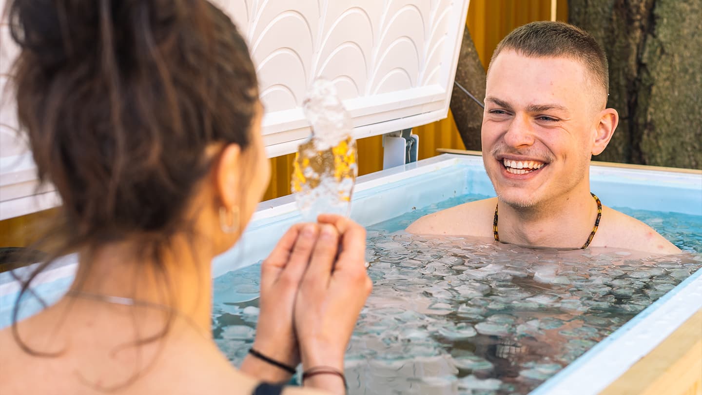 Cold Plunge Ice Bath Session Smiling man sitting in an ice bath during a cold plunge session