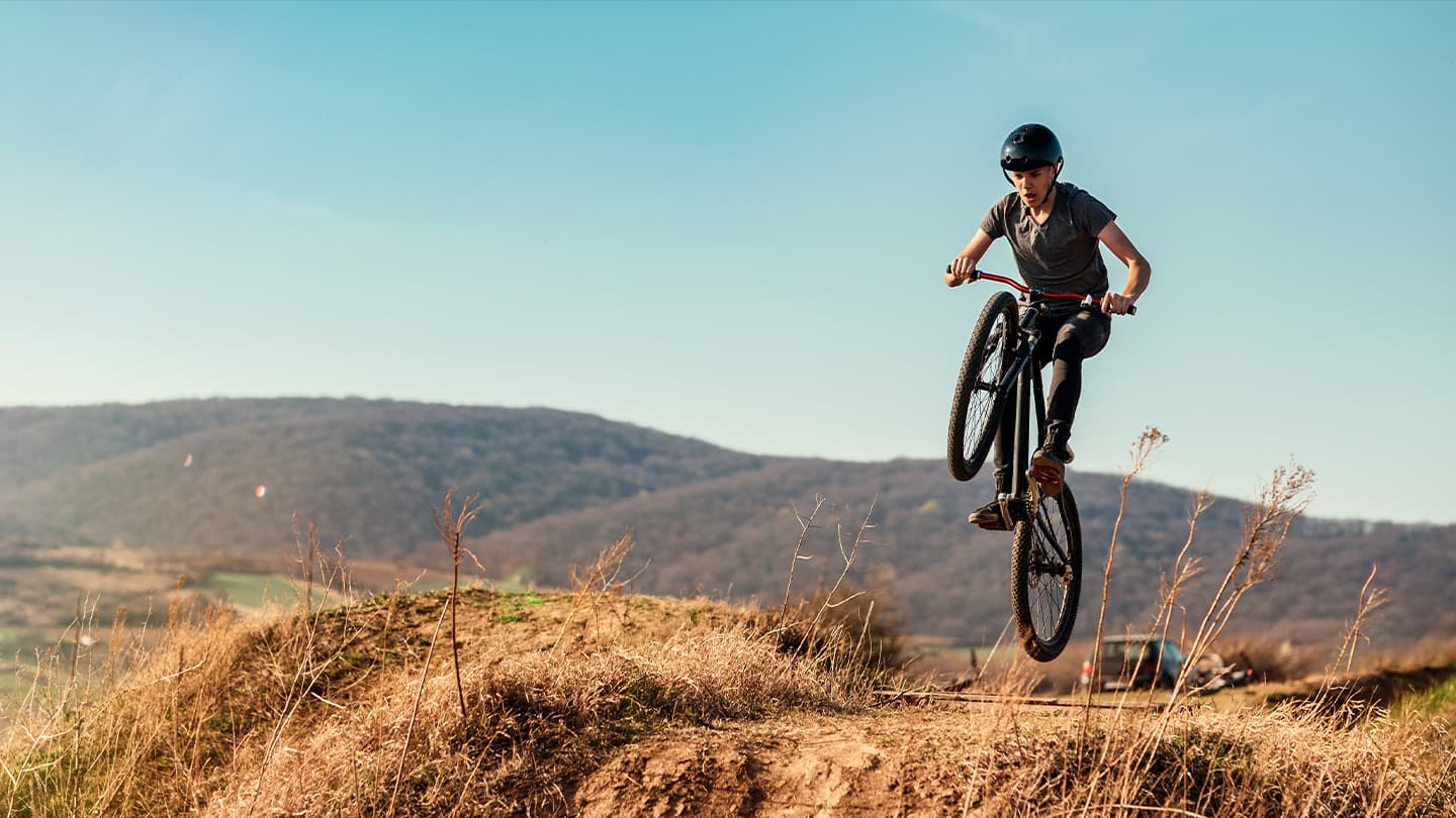 Mountain Bike Jump on Dirt Trail Young rider launching off a dirt jump on a mountain bike