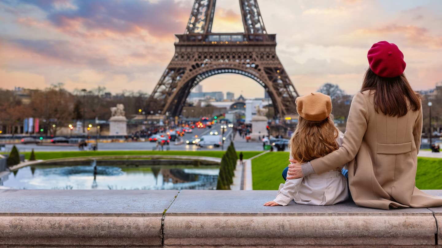 Family Moment at Eiffel Tower Paris Mother and child wearing berets sitting overlooking Eiffel Tower at sunset