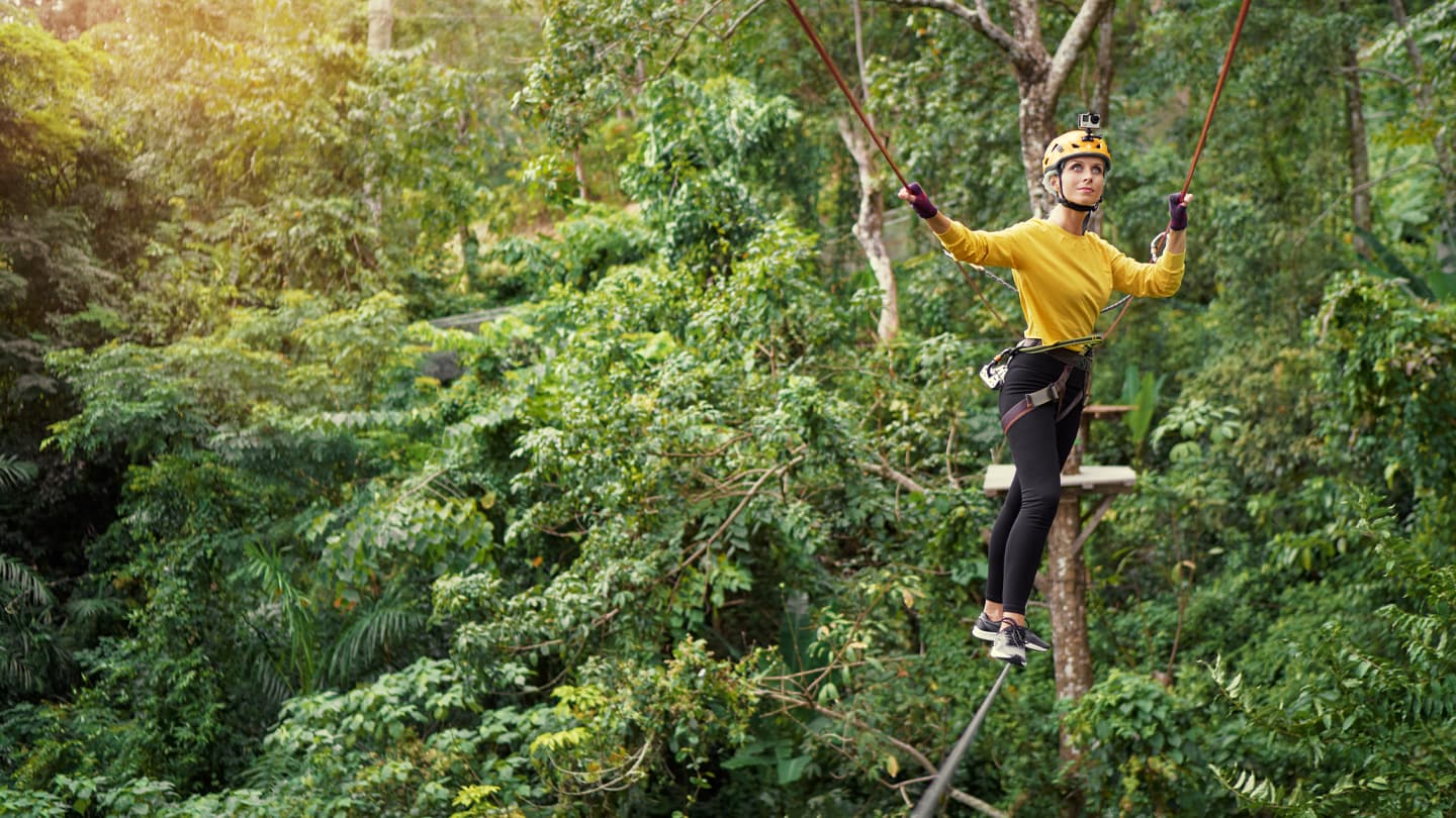 Jungle Canopy Zip Line Adventure Woman in yellow shirt zip lining through lush tropical jungle canopy