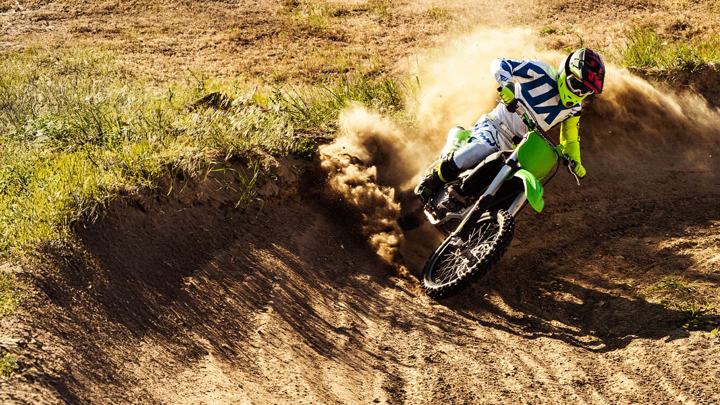 Motocross Rider Cornering on Dirt Track Motocross rider leaning into a sharp dirt track corner with a cloud of dust.