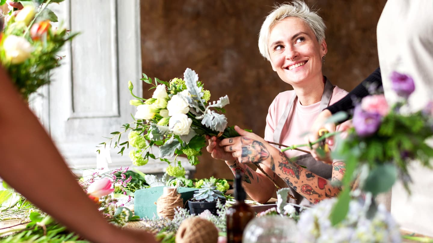 Florist Arranging Fresh Flower Bouquet Smiling tattooed female florist arranging white flower bouquet in workshop