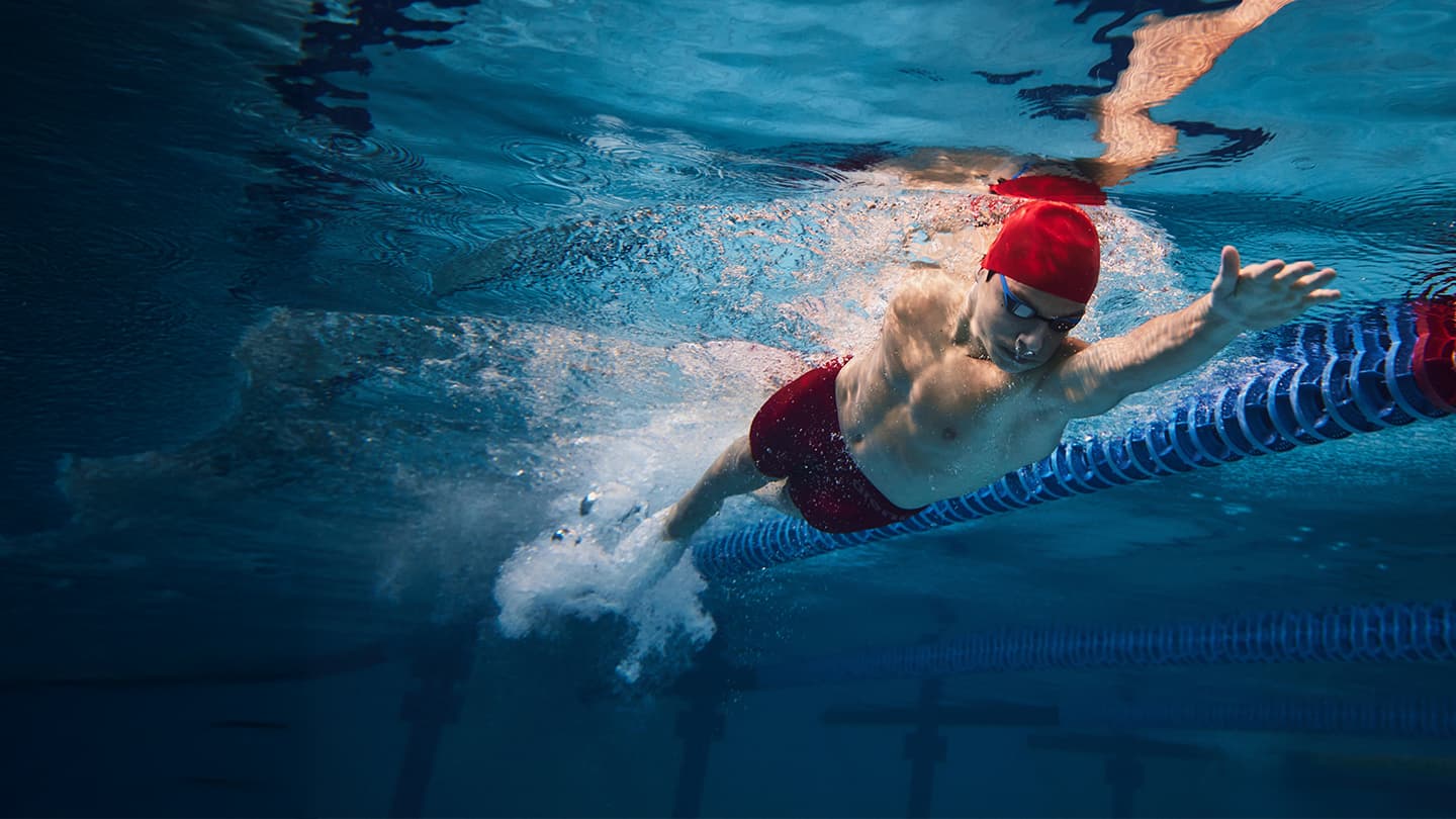 Competitive Swimmer in Pool Lane Male competitive swimmer powering through a pool lane underwater
