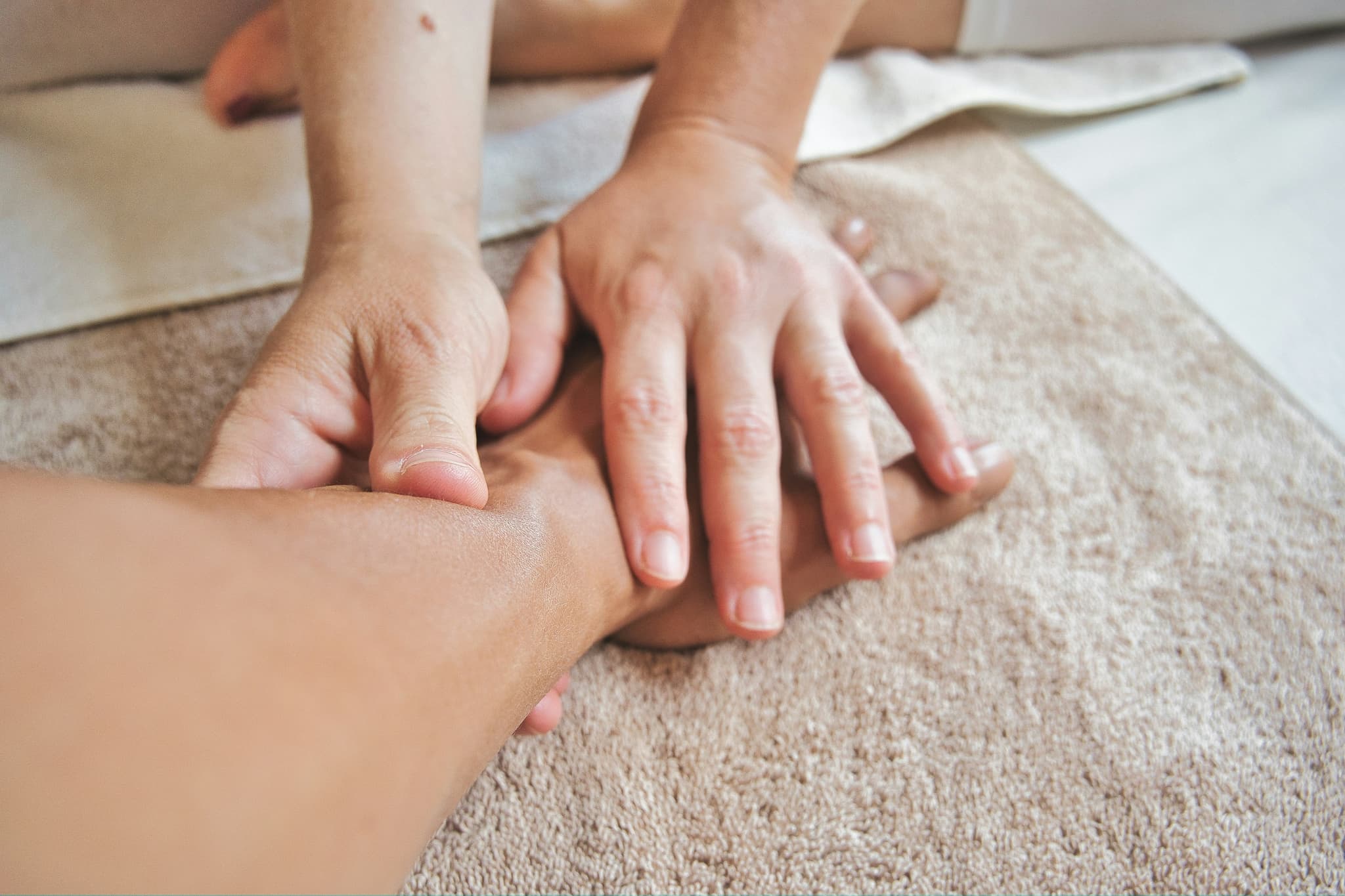 Hands Stacked Together on Carpet Child's hands stacked on top of an adult's hand on a beige carpet.