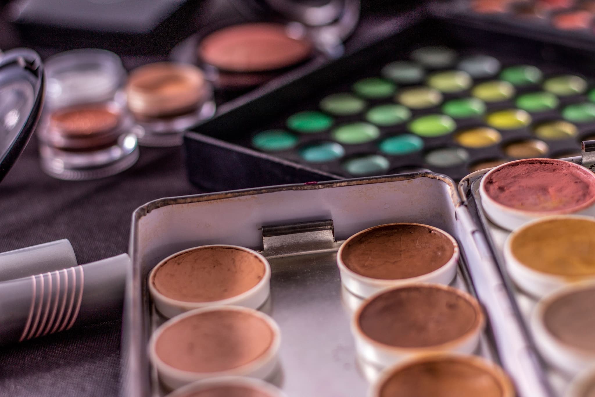 Makeup Cosmetics and Eyeshadow Palette Makeup cosmetics collection with foundation shades, eyeshadow palettes, and brushes arranged on a dark surface.