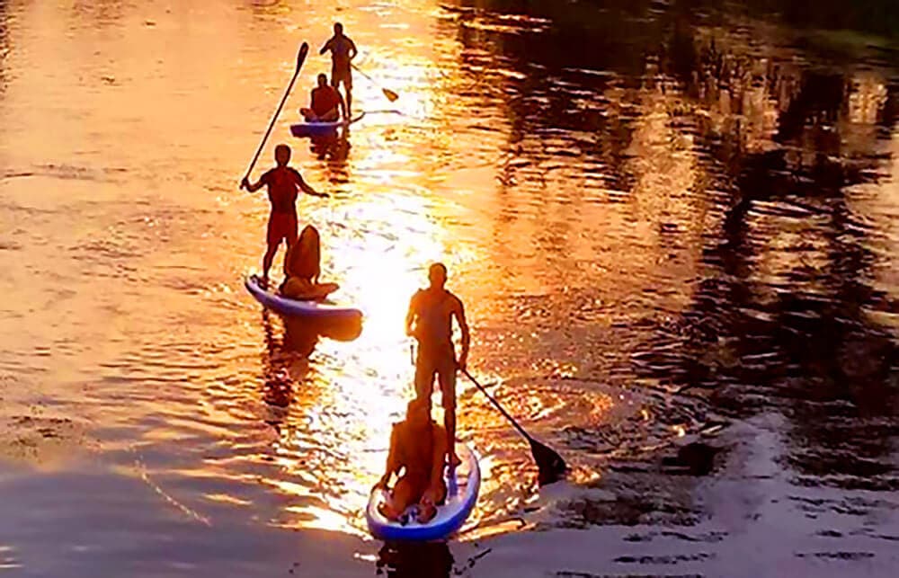 Paddleboarders at Golden Hour Multiple paddleboarders on the water during golden hour with warm sunlight reflecting off the surface.