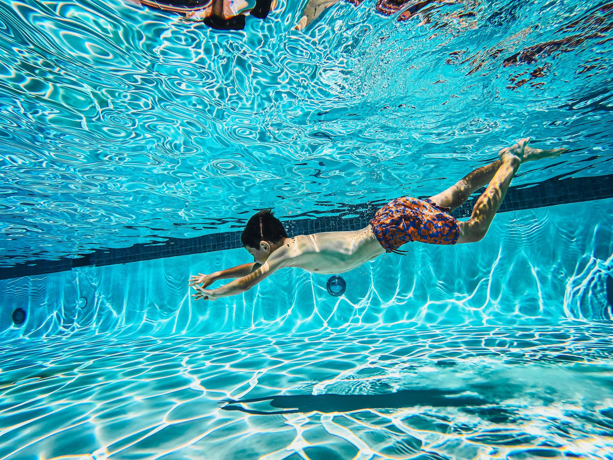 Child swimming butterfly stroke underwater Child swimming underwater and performing butterfly stroke in a clear blue pool.