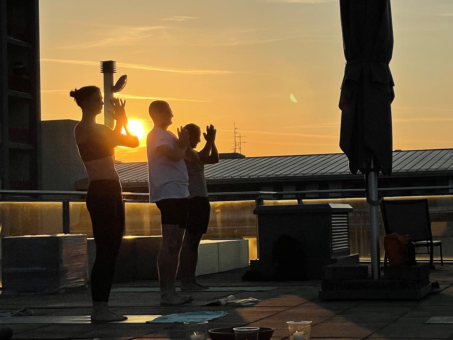 Rooftop Yoga Practice at Sunset People practicing yoga on a rooftop during sunset with a golden sky in the background.