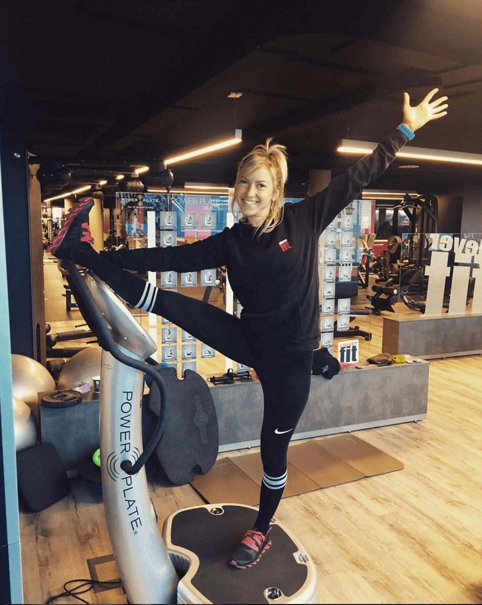 Balancing on a Vibration Plate Woman balancing on one leg on a vibration plate machine in a gym.