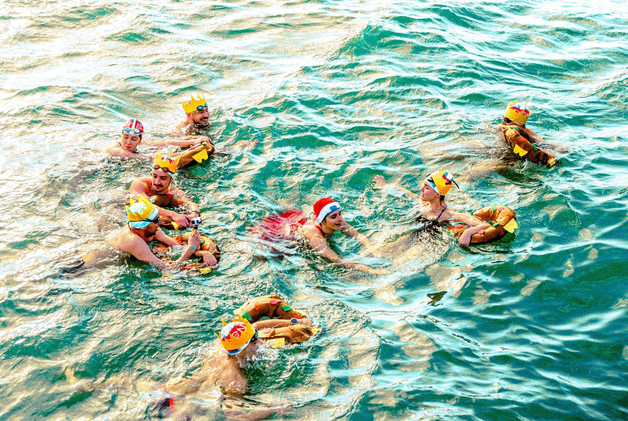 Swimmers in Ocean Waves With Safety Gear Group of swimmers in ocean waves wearing yellow caps and safety gear during a water activity.