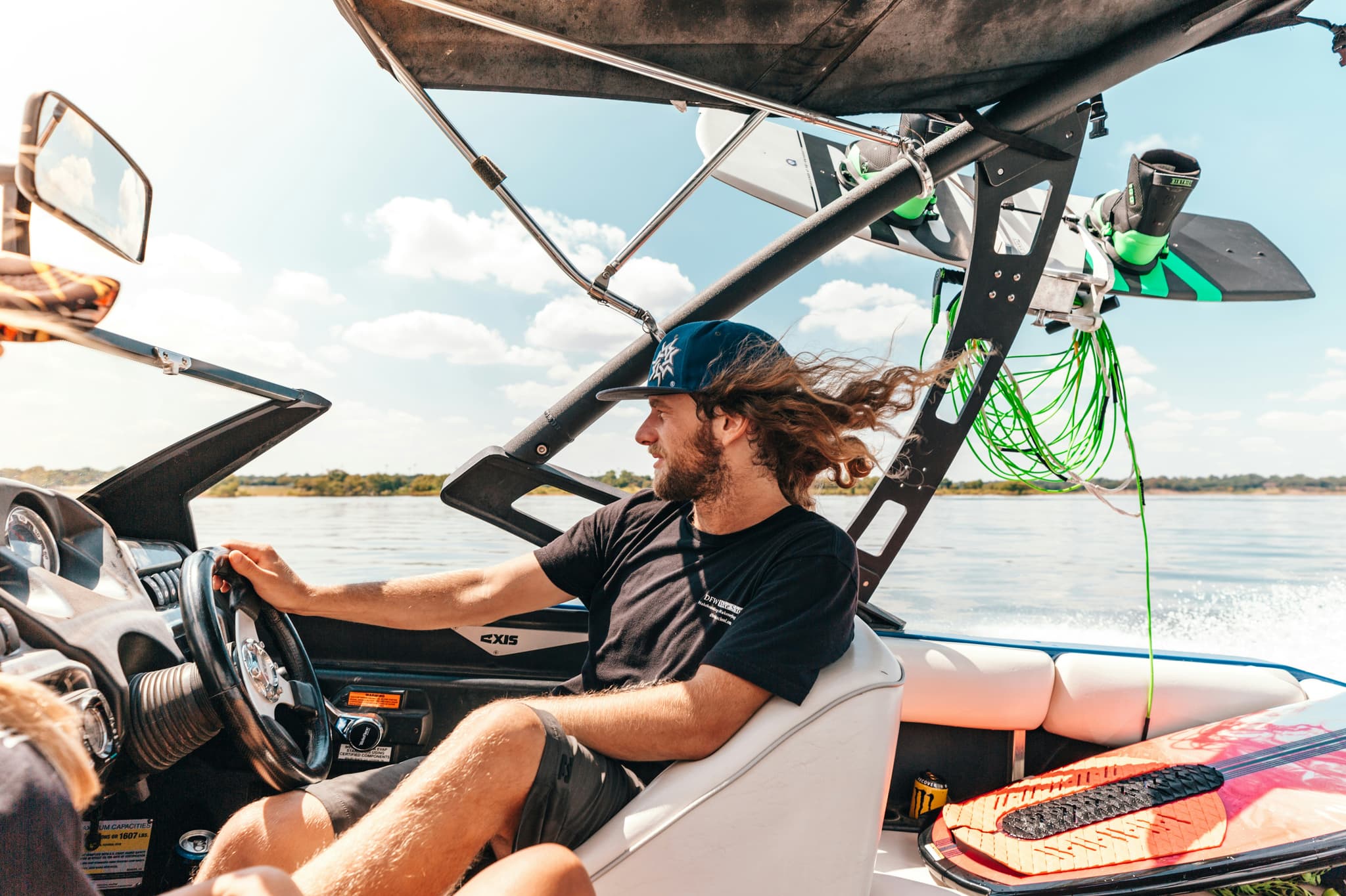 Wakeboard Boat Operator on Water Person at the helm of a wakeboard boat on open water with green rope and equipment visible.