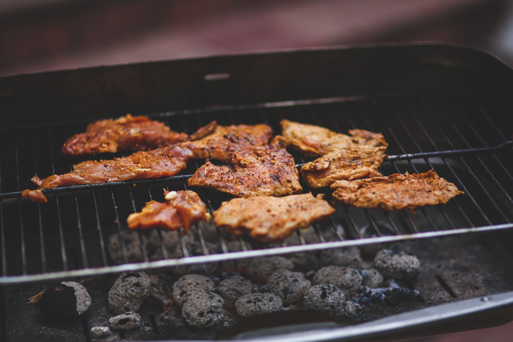 Grilled Meat Patties on Charcoal Grill Seasoned meat patties cooking on a grill grate with hot charcoal below.