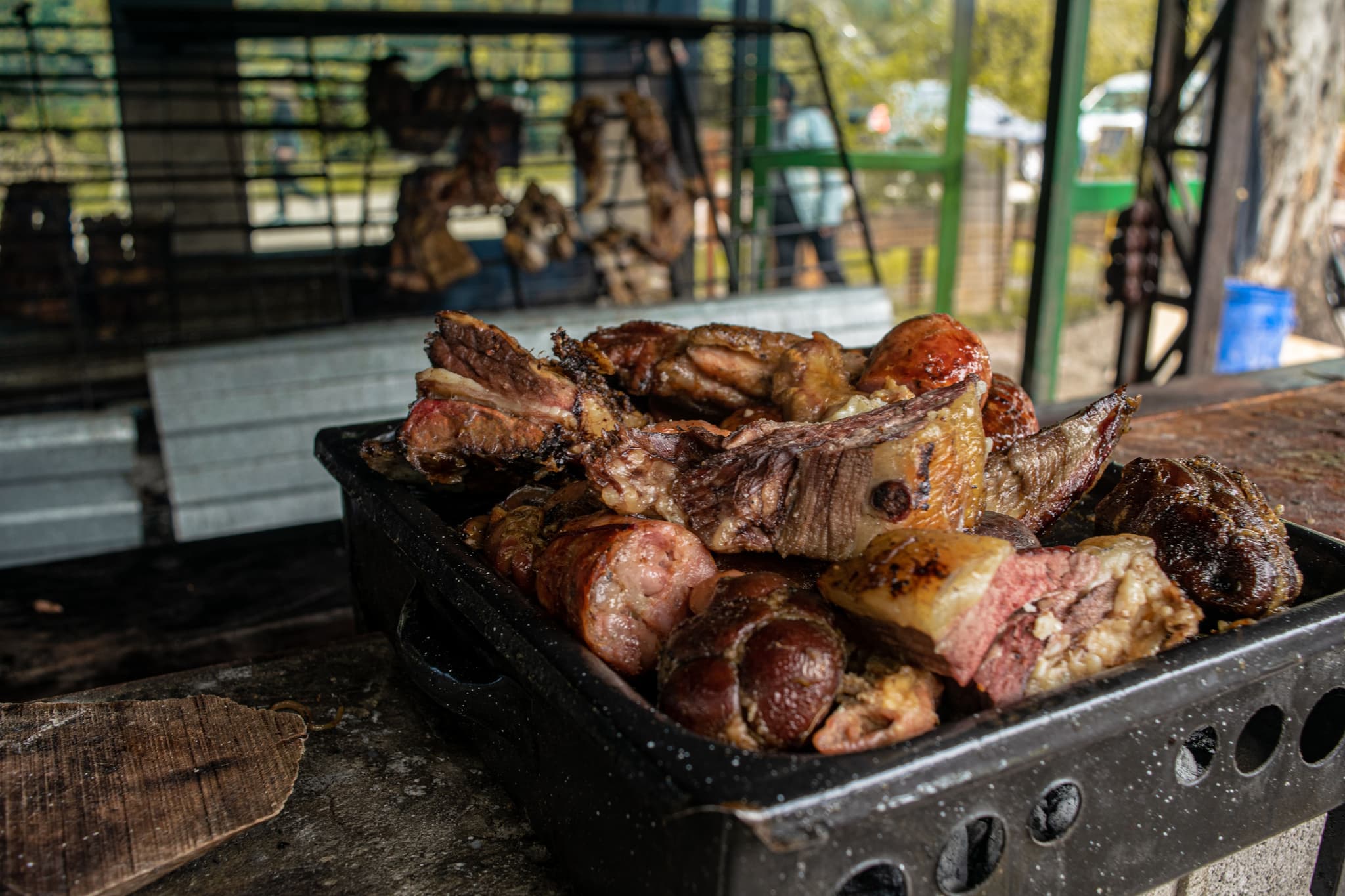 Grilled Meat Cuts Outdoor Barbecue Assorted grilled meat cuts on a black metal platter at an outdoor barbecue.
