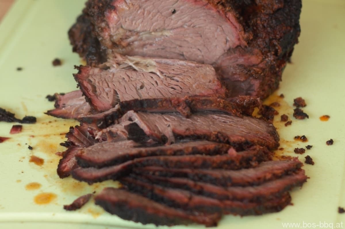 Sliced beef brisket with roasted crust Sliced beef brisket with roasted crust on a yellow plate, garnished with coarse salt and pepper.
