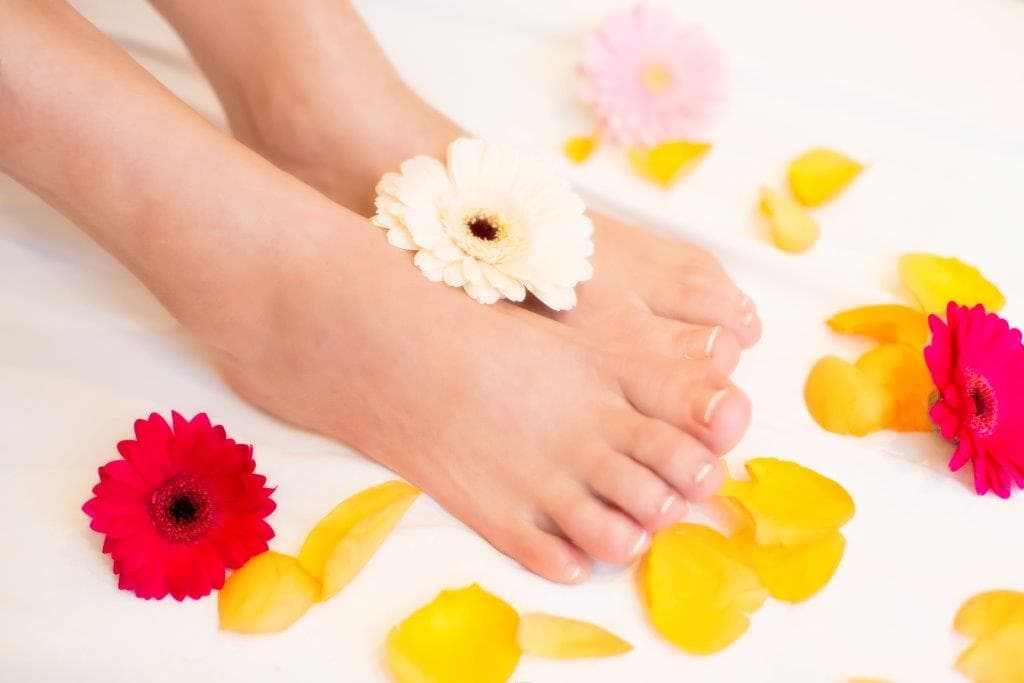 Feet With Gerbera Flowers and Petals Bare feet resting among colorful gerbera flowers and petals in a spa setting.