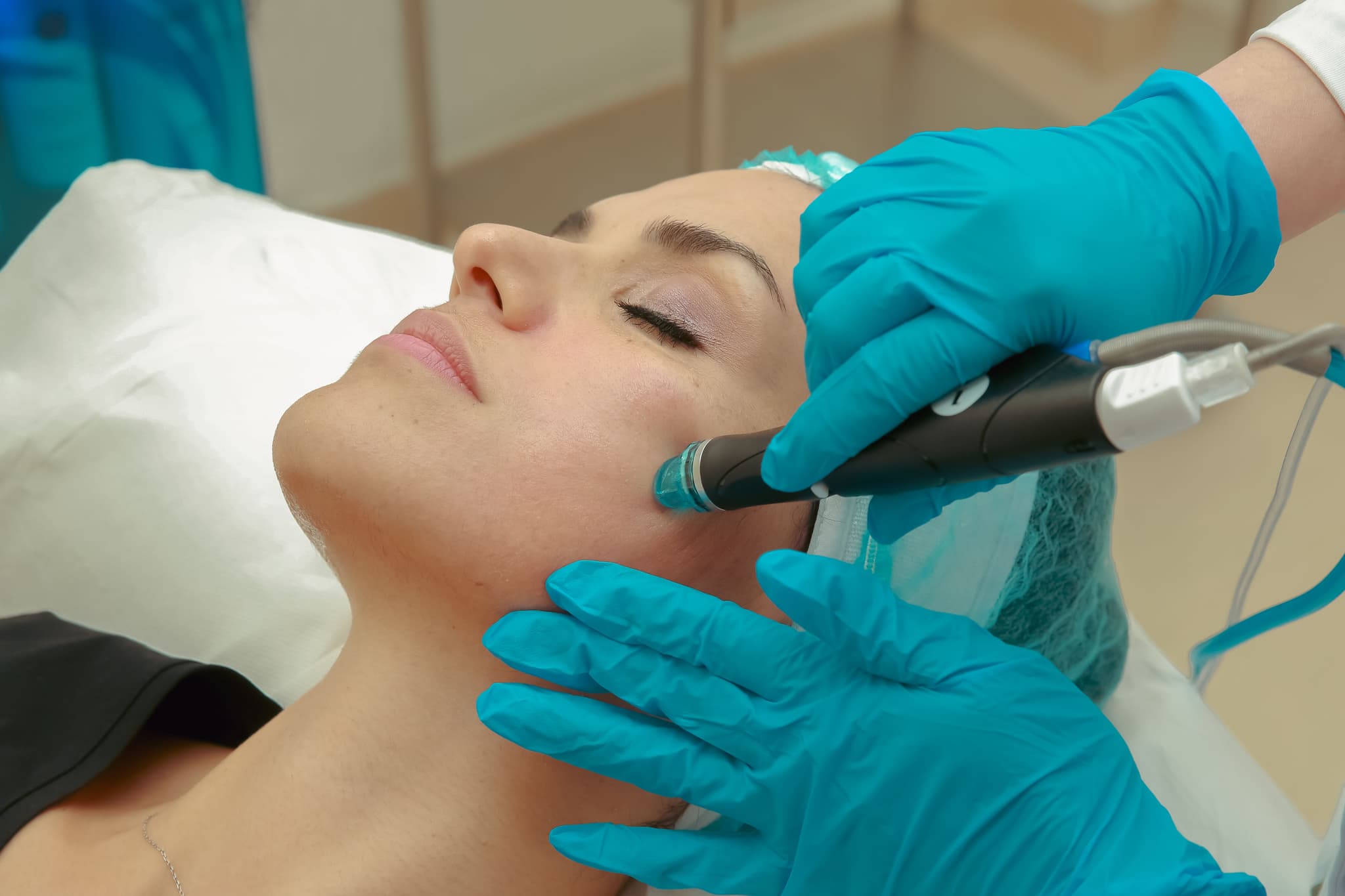 Facial Hydrodermabrasion Skincare Treatment Esthetician using a hydrodermabrasion device on a client's cheek during a facial treatment.