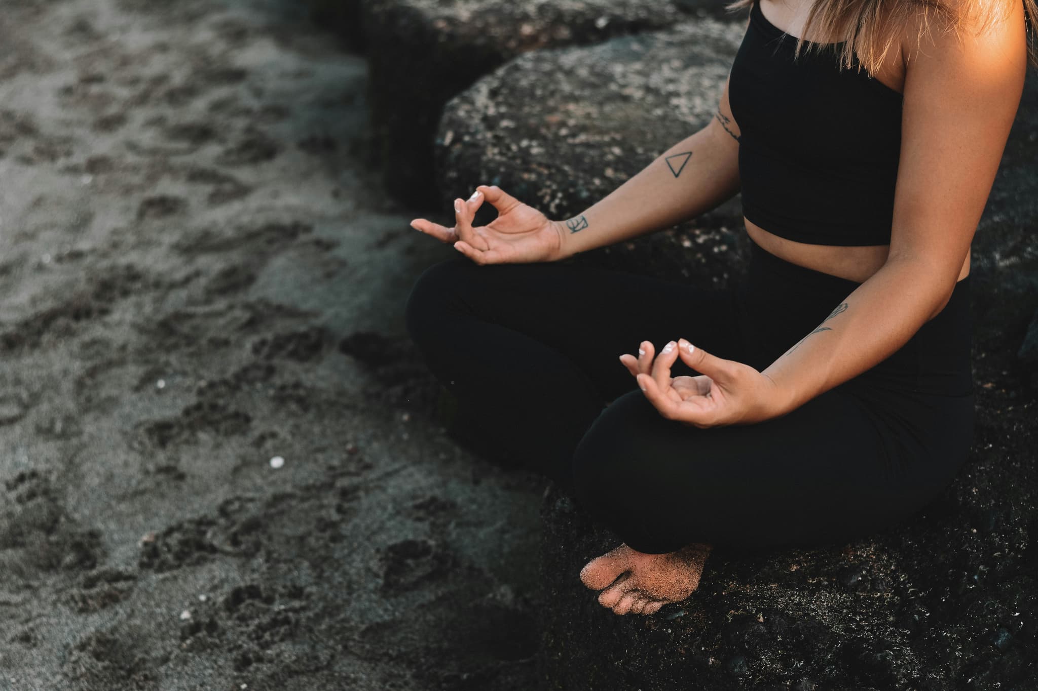 Yoga Meditation Practice on Beach Person in black athletic wear practicing yoga meditation pose on dark sand beach.