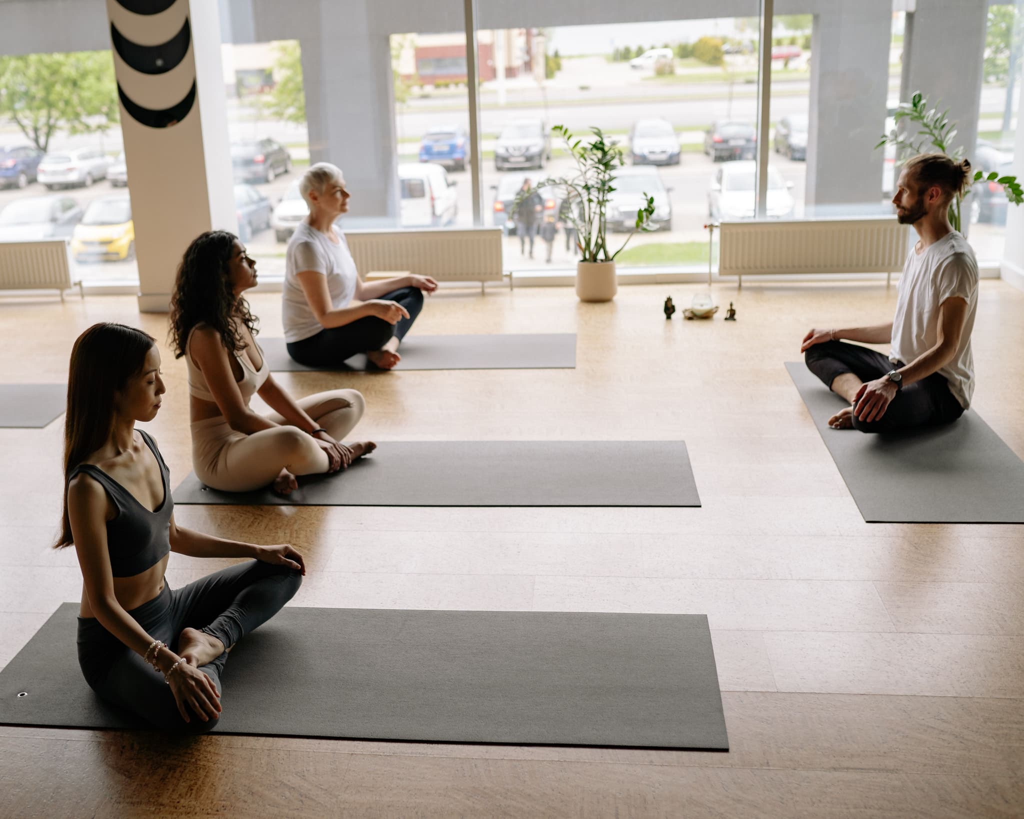 Group Yoga Class in Bright Studio Group of people practicing yoga in a bright studio with large windows overlooking a parking lot.
