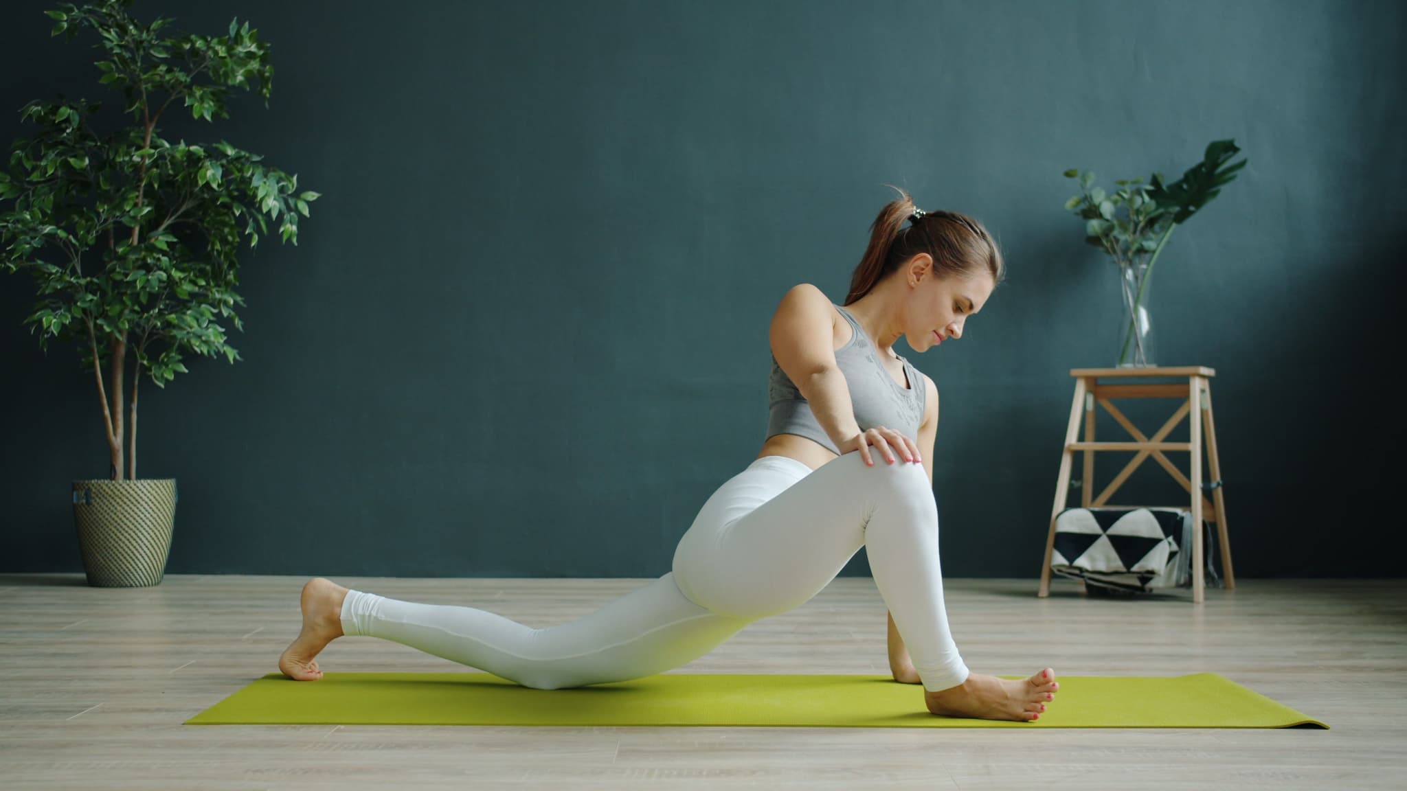 Indoor Yoga Stretch in Lunge Pose Woman stretching in a low lunge pose on a yoga mat indoors.
