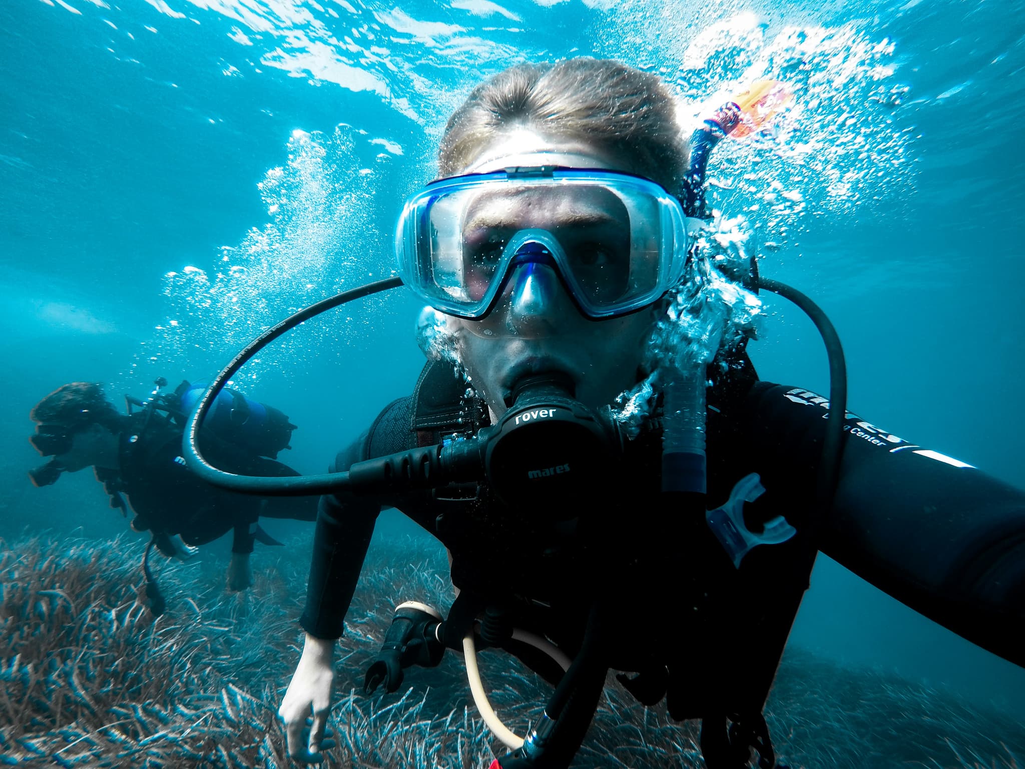 Diver in Close-Up Portrait Underwater Close-up of a diver wearing a mask and regulator, surrounded by rising air bubbles underwater.