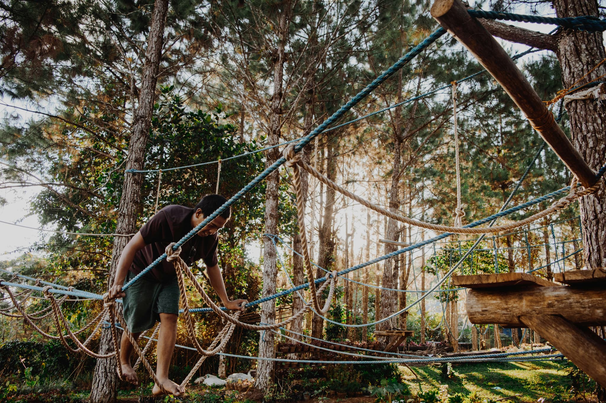 Rope Obstacle Course in Forest Person navigating a rope obstacle course suspended between trees in a forested area.