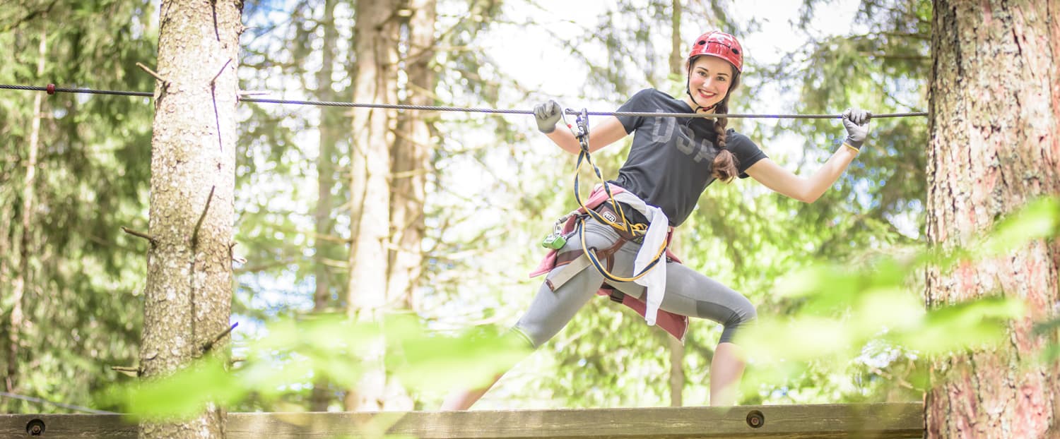 Zipline Adventure Through the Forest Person in helmet and harness crossing a zipline course in a forest.