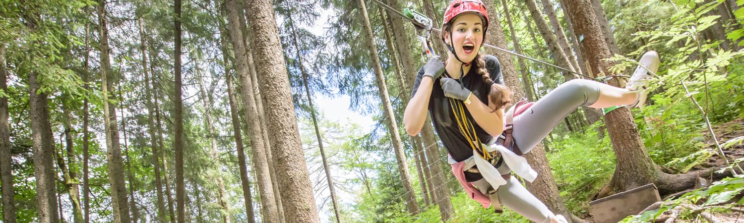 Ziplining Through the Forest Person ziplining through a forest, wearing a helmet and safety harness.