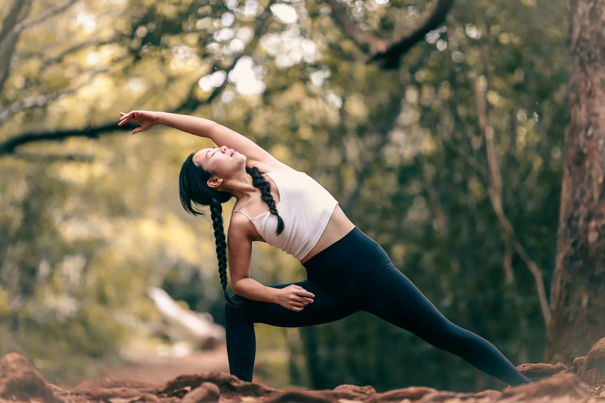 Outdoor Yoga Side Stretch in Forest Person performing a side stretch yoga pose outdoors among trees and natural woodland.