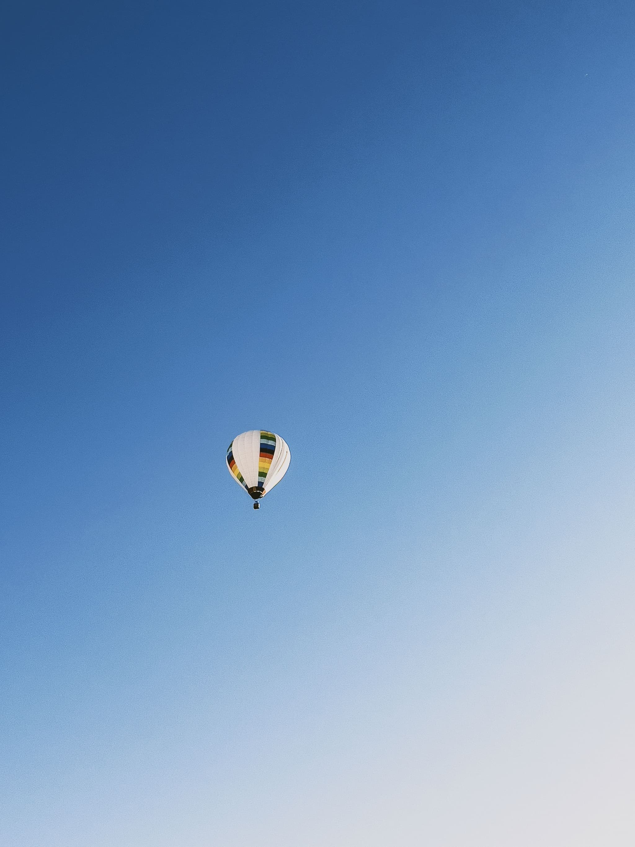Hot Air Balloon in Clear Sky Hot air balloon with white and striped envelope floating against a clear blue sky.