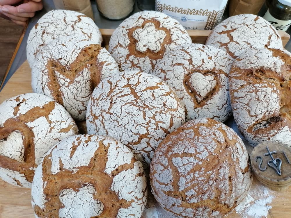 Artisan Bread Loaves With Flour Crust Multiple artisan bread loaves with white flour-dusted crusts and deep scoring patterns on a wooden surface.