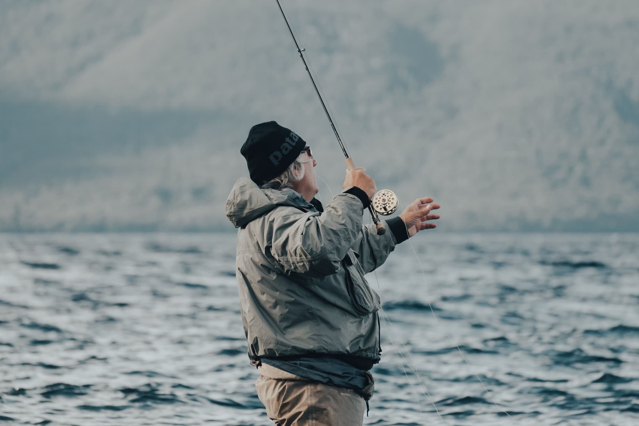 Fly Fishing in Open Water Person fly fishing in open water, holding a fly rod with a visible fly reel on their wrist.
