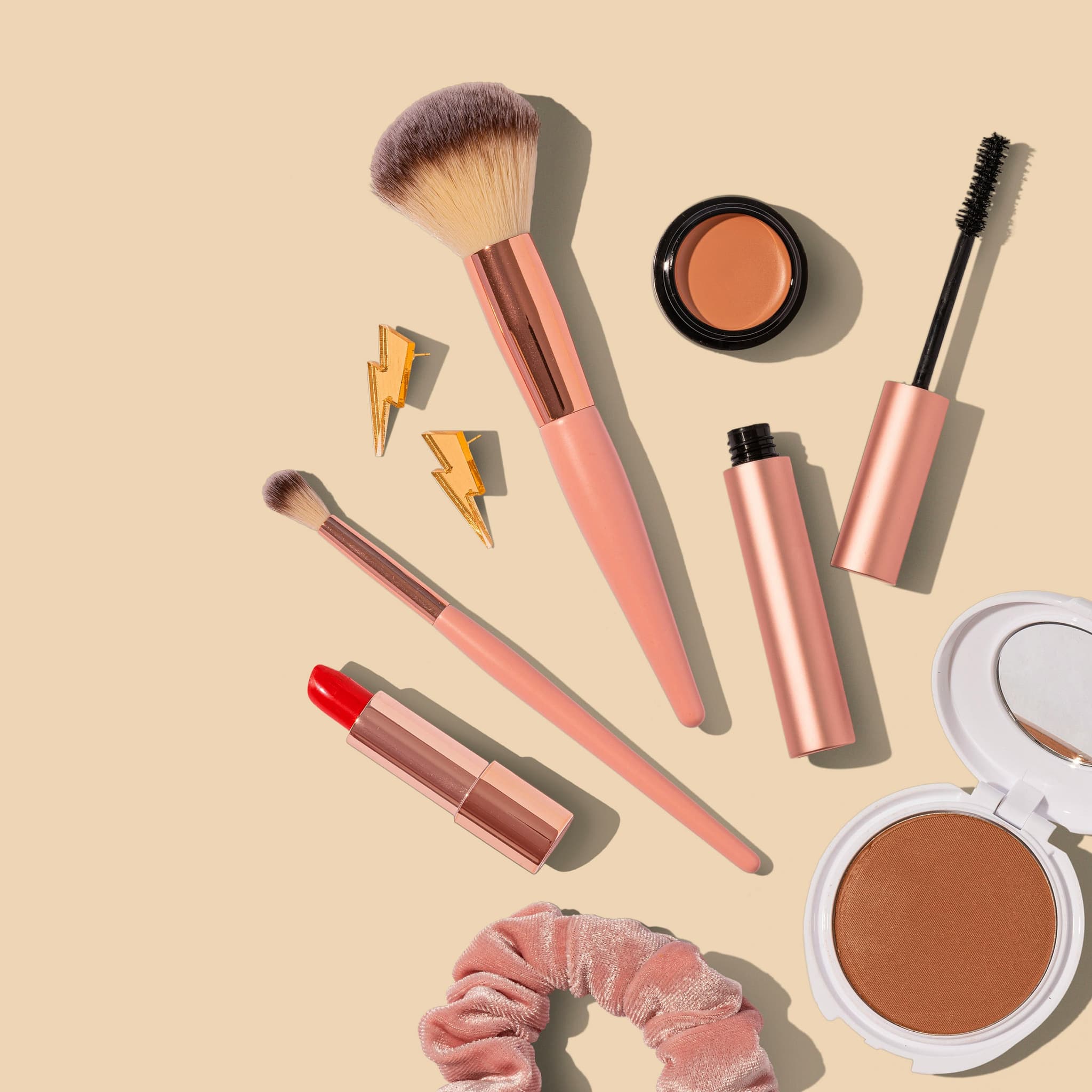 Makeup and Cosmetics Collection with Brushes Flat lay of makeup products with brushes, lipstick, mascara, eyeshadow, blush, and powder compacts on beige background