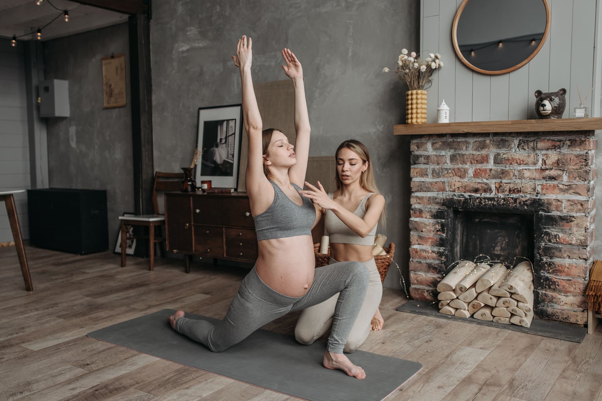 Prenatal Yoga Lunge With Instructor Pregnant woman in a lunge yoga pose with an instructor guiding her arm.