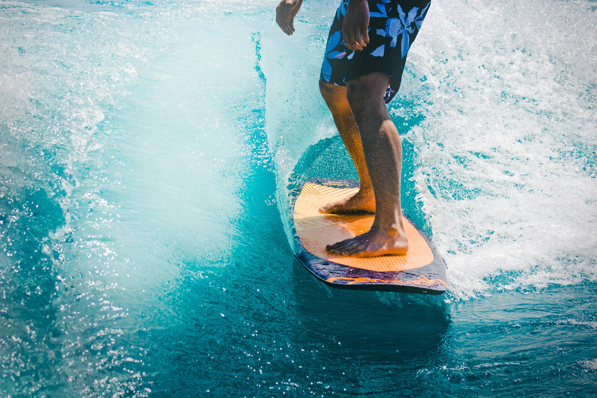 Surfer Riding a Teal Wave Barefoot surfer riding a teal wave on an orange surfboard.