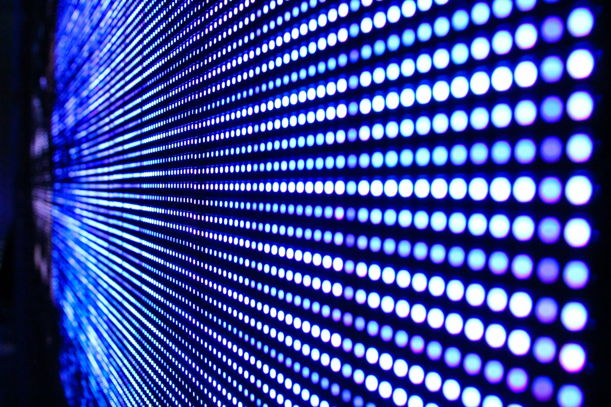 Blue LED Display Grid Perspective Close-up view of a blue LED display grid with rows of illuminated circular lights receding into perspective.