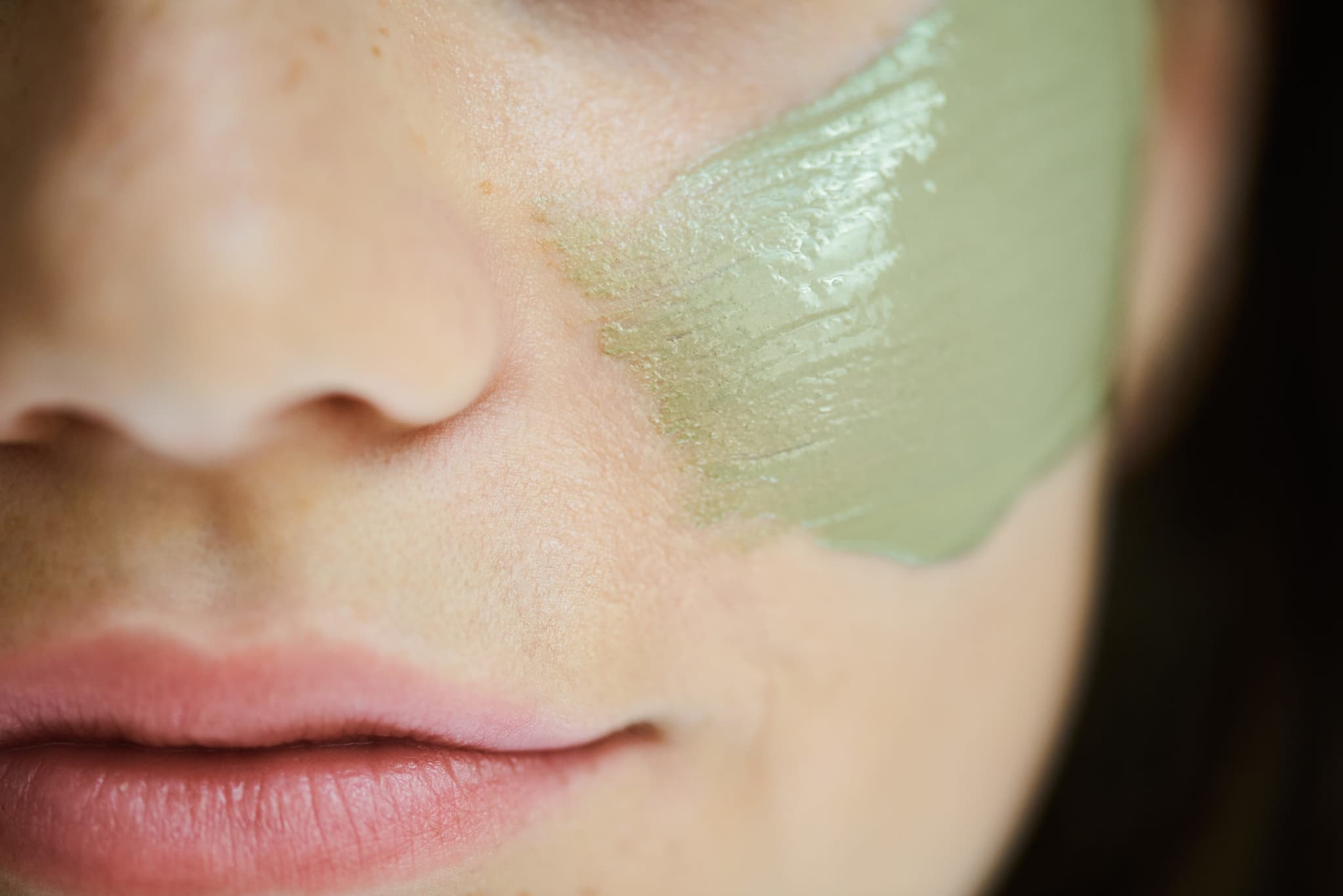 Hautpflege-Behandlung mit grüner Maske Nahaufnahme eines Gesichts mit einer grünen Hautpflege-Maske auf der Wangenpartie.