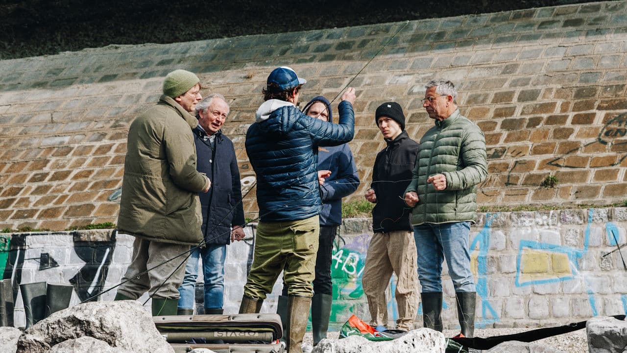 Group Fishing Lesson Outdoors Group of people learning to fish together outdoors against a brick wall.