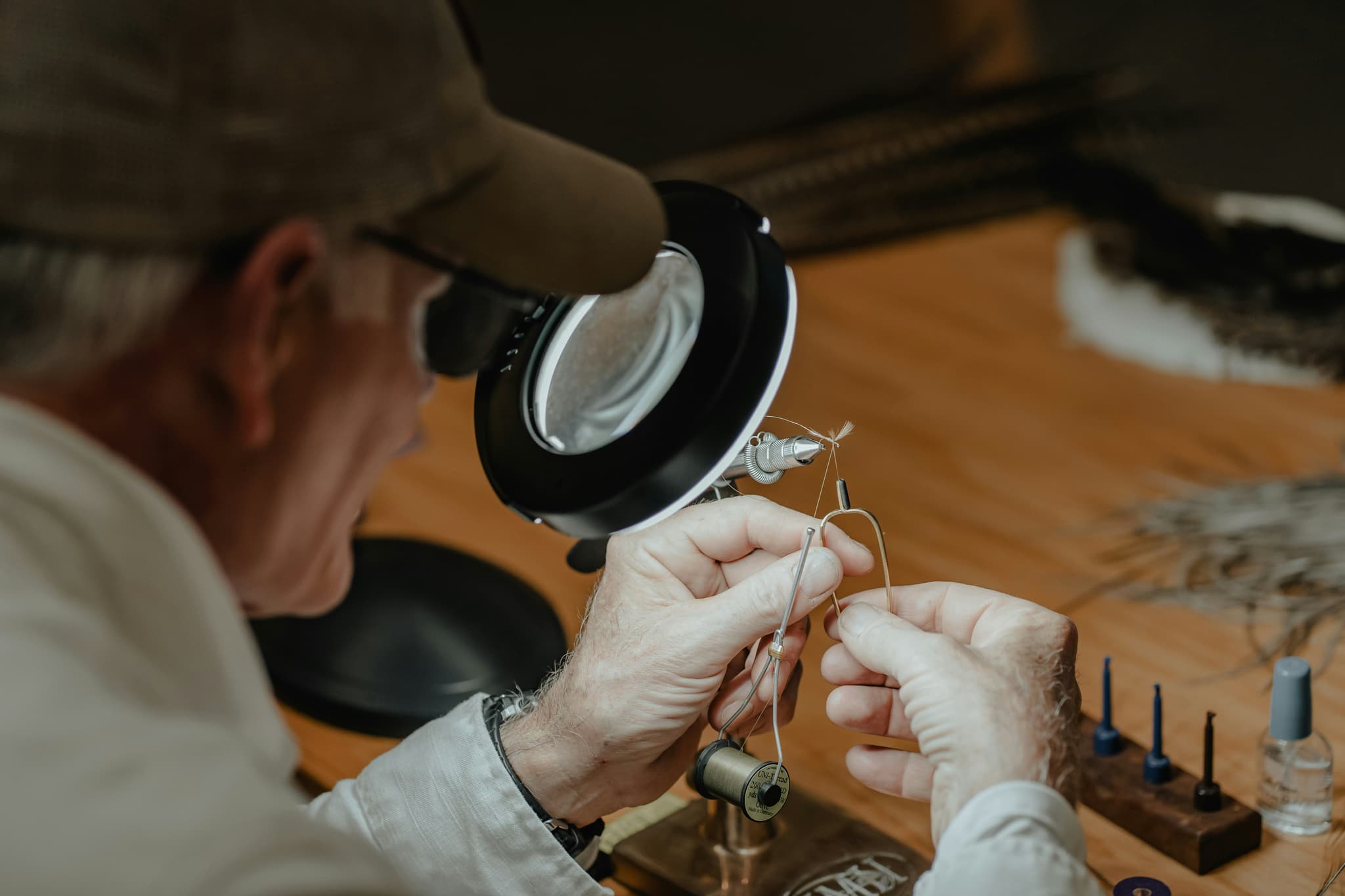 Detailed Component Inspection with Magnifying Glass Person examines a small electronic component on a wooden workbench using a handheld magnifying glass.