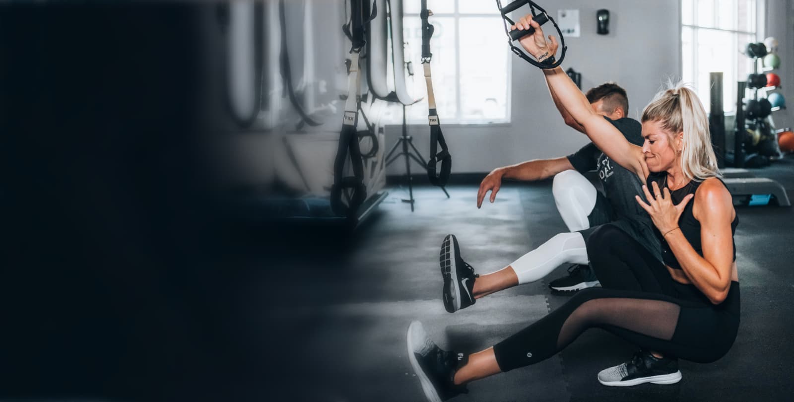 TRX Suspension Training Session Woman performing TRX suspension training exercise with personal trainer guidance in modern gym
