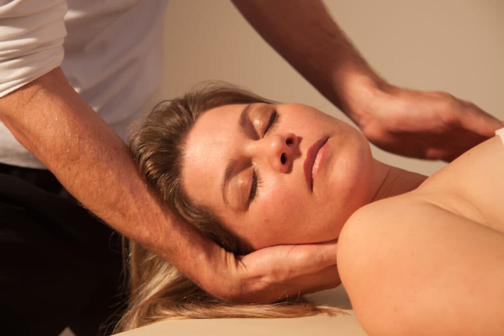 Relaxing Facial Massage Therapy Therapist's hands gently supporting a woman's head during a facial massage.