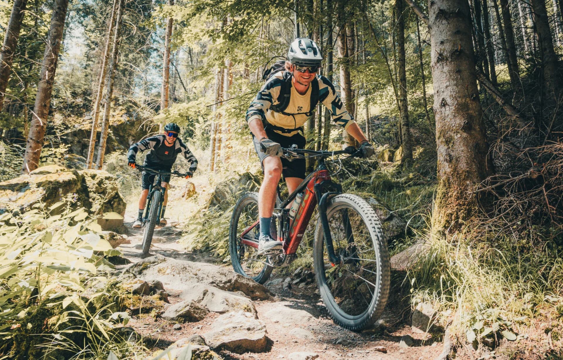 Mountain bikers on a rocky forest trail Two mountain bikers ride along a rocky trail through a forest.