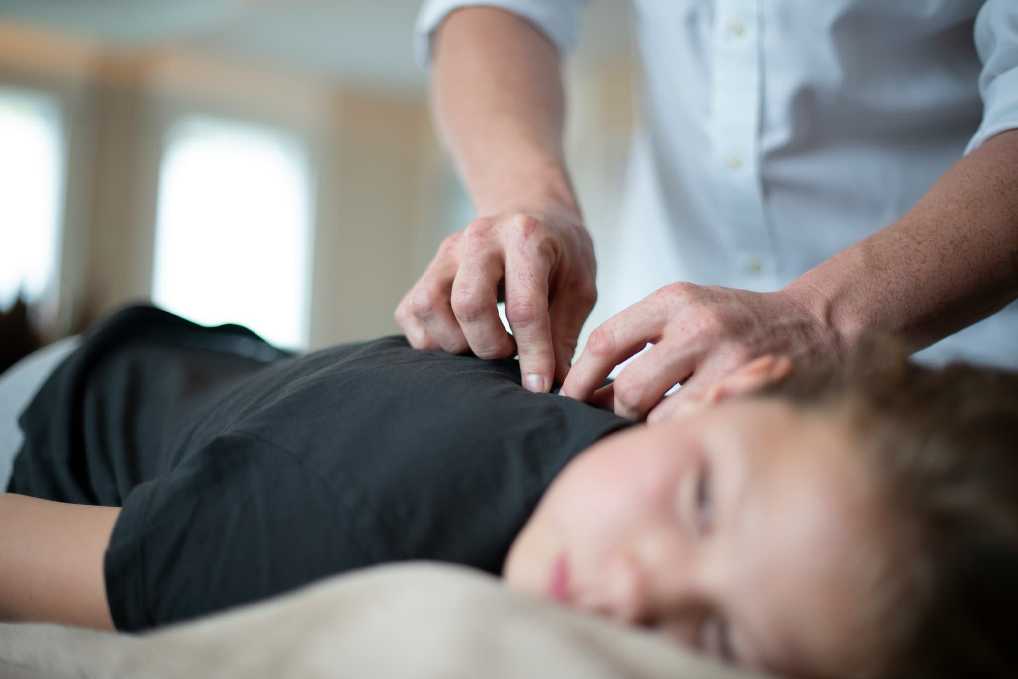 Massage Therapy Treatment Session Massage therapist applying pressure to a client's back during a treatment session.