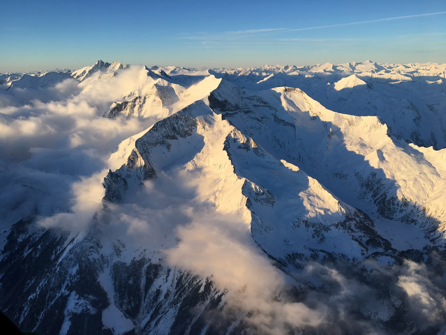 Snowy Mountain Peaks Above the Clouds Snow-capped mountain peaks rising above clouds at sunset.