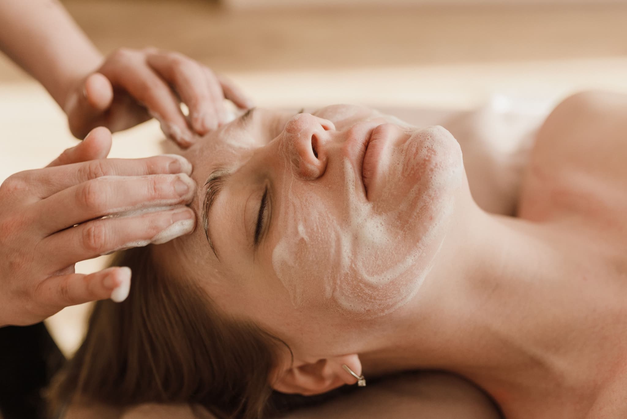 Facial Massage Therapy Treatment Therapist performing a facial massage on a relaxed client during a spa treatment session.