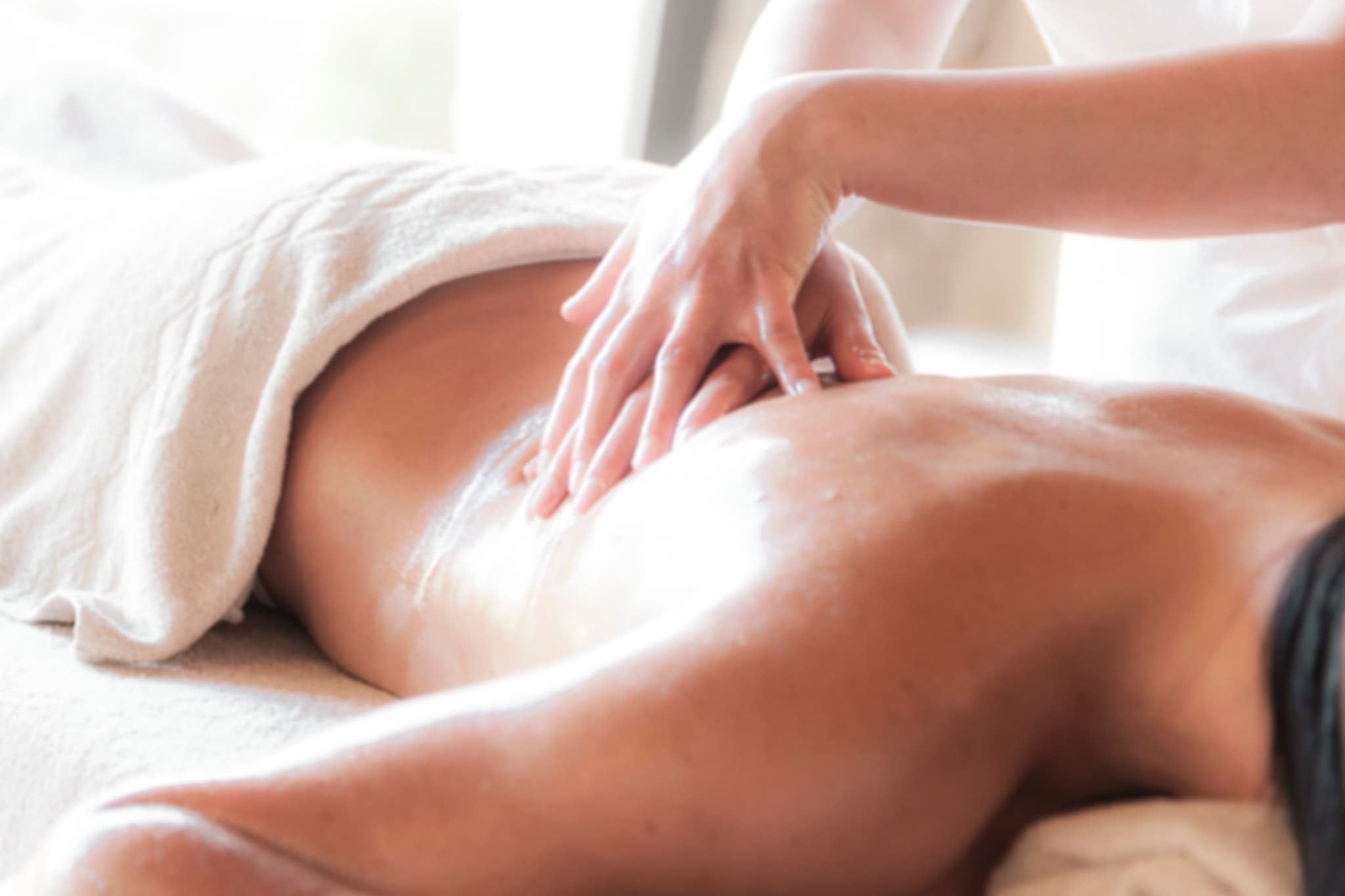 Massage Therapy Treatment Session Massage therapist's hands applying treatment to a client's back during a wellness session.
