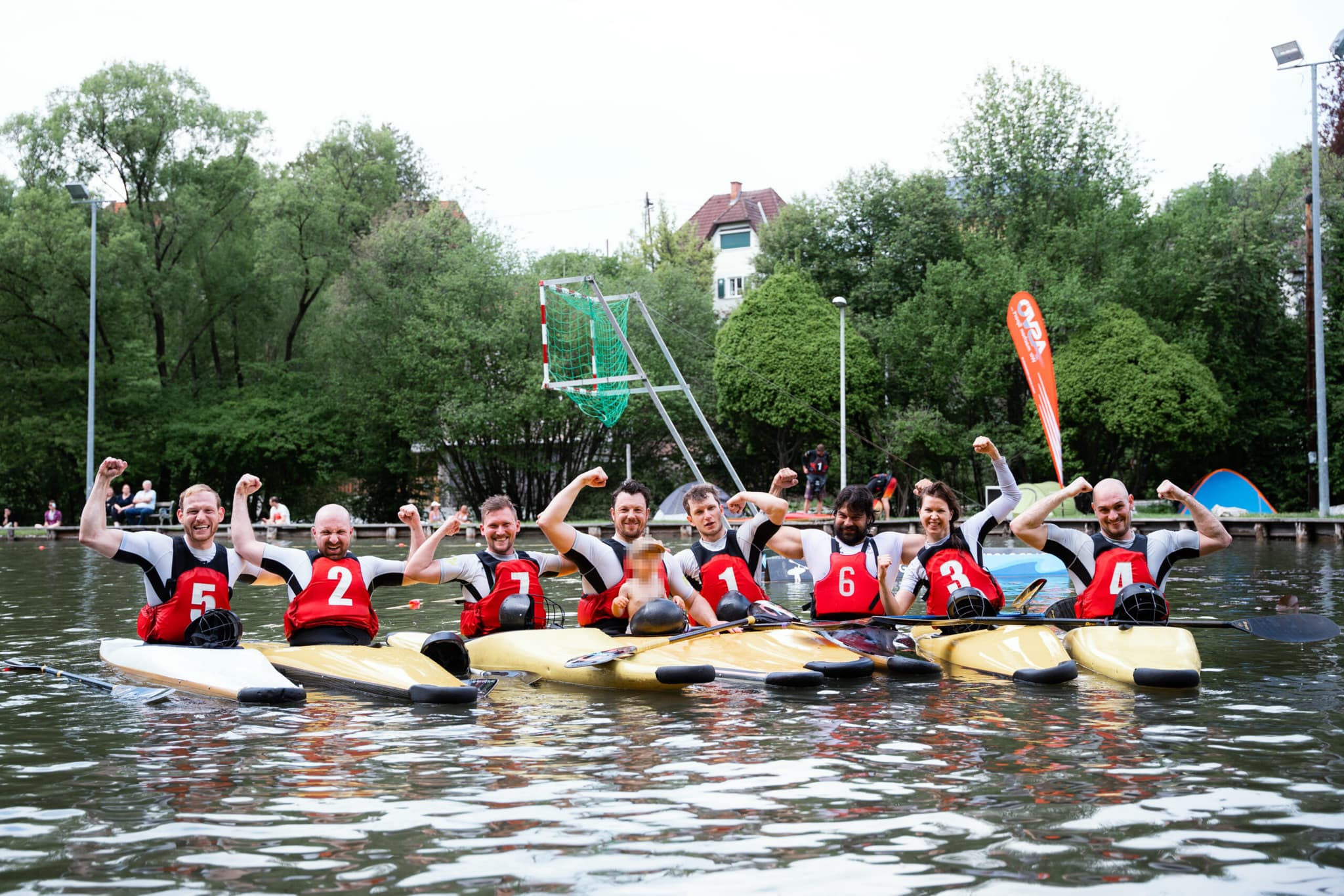 Kayak Polo Team Celebrates on the Water Kayak polo players cheering with raised fists on the water.